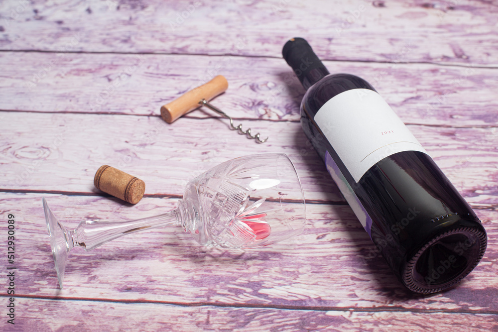 Red wine bottle, glass and corkscrew on a wooden background, top view.
