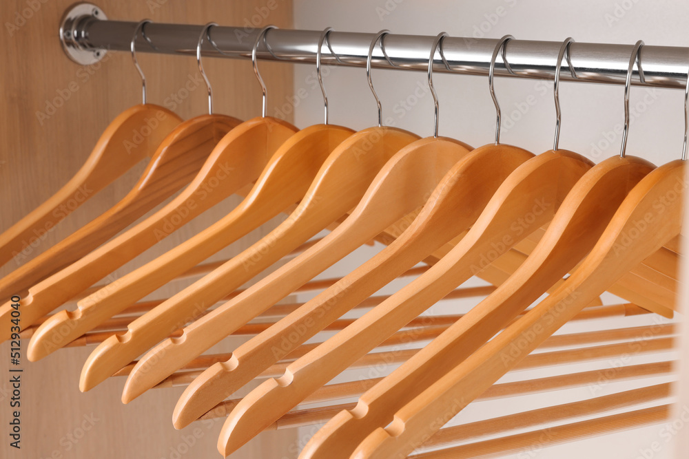 Set of clothes hangers on wardrobe rail, closeup - obrazy, fototapety, plakaty 