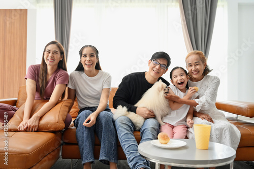 Portrait of happy Asian family with a dog having fun together at home.