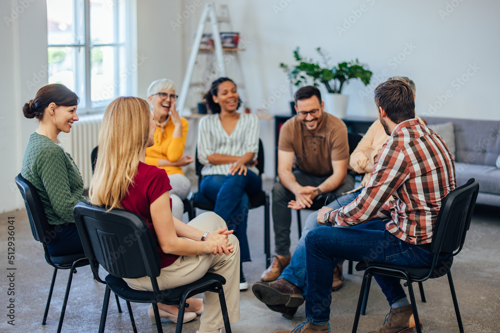 Group of people, sitting in a circle, laughing and talking to each other, during the group therapy. - obrazy, fototapety, plakaty 