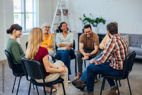 Group of people, sitting in a circle, laughing and talking to each other, during the group therapy. photo
