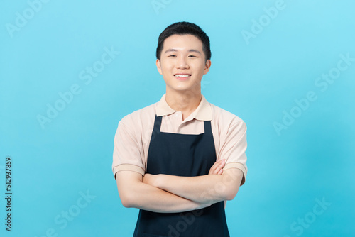 Handsome young man in apron is looking at camera and smiling