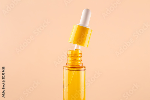 glass yellow bottle with pipette with essential oil on beige background top view. Aromatic cosmetic product for skin hair care Moisturizing beauty product with vitamin C close up