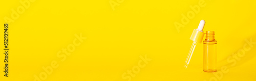 glass yellow bottle with pipette with essential oil on a yellow background top view. Aromatic cosmetic product for skin hair care Moisturizing beauty product with vitamin C close up. dropper
