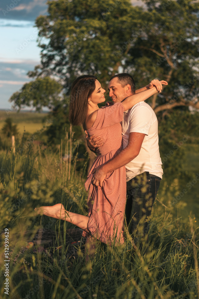 A couple of lovers man and woman hugging and kissing in a meadow at sunset.Love,passion,youth,happiness,summer concept.