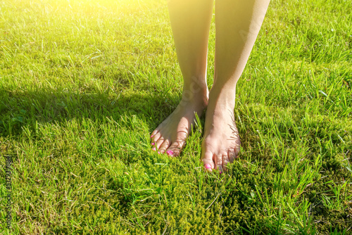 Woman legs on green grass. Walk barefoot on fresh green grass