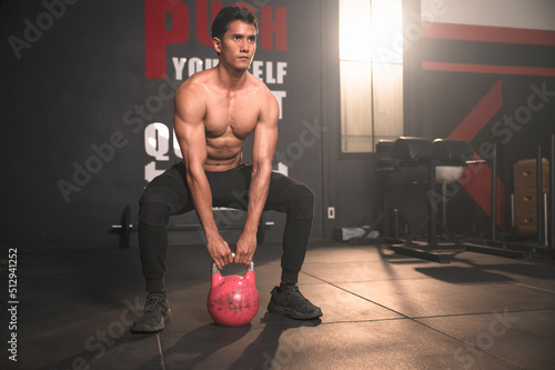 Asia sport man training with kettlebell in fitness gym