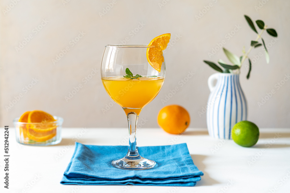 Yellow bird cocktail with rum, orange and lime juice, fruits, blue napkin and vase with olive branch. Copy space
