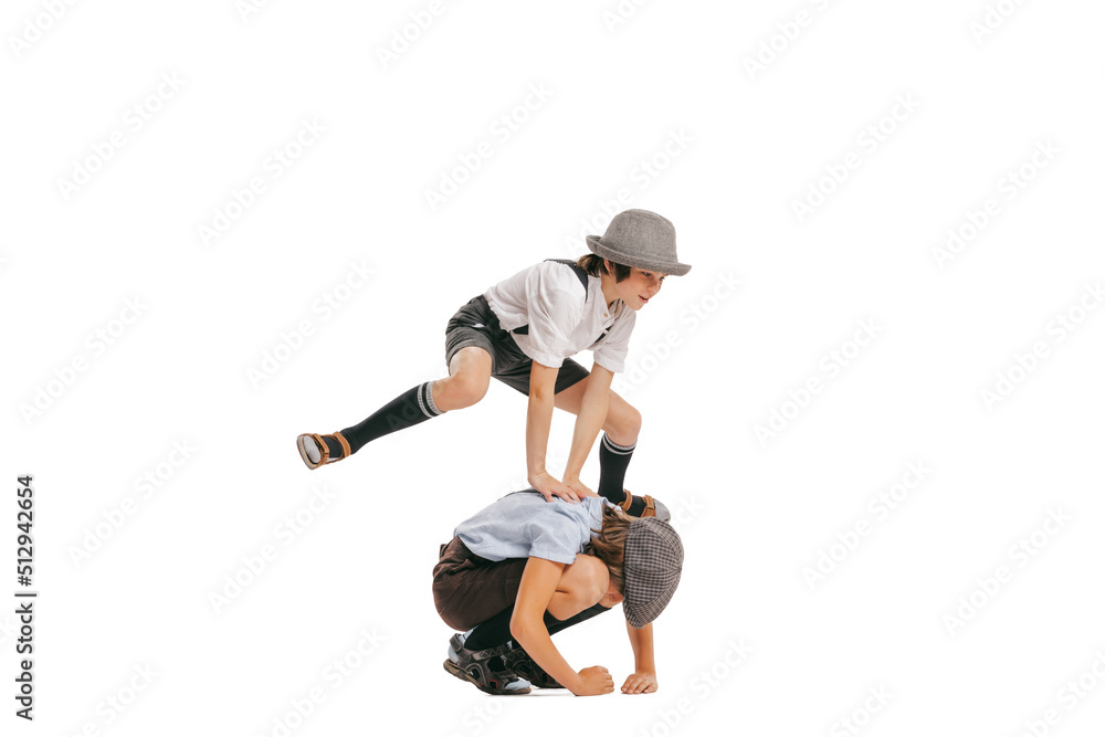 Happy school age boys, kids wearing retro clothes playing isolated over white background. Concept of childhood, vintage summer fashion style