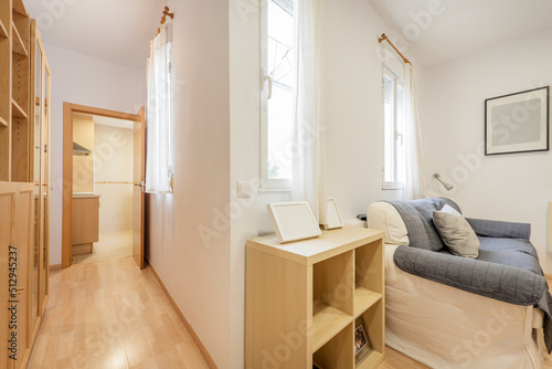 Living room with several windows  light fabric sofa bed and hallway with oak furniture