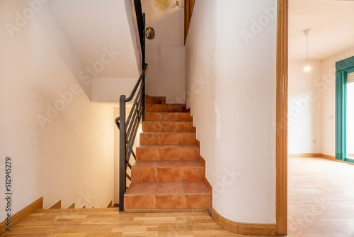 Interior stairs of a residential single-family home with parquet floors combined with clay tile steps