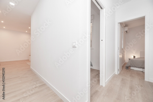 Empty house with corridors with light oak floors, doors to other rooms and white painted walls