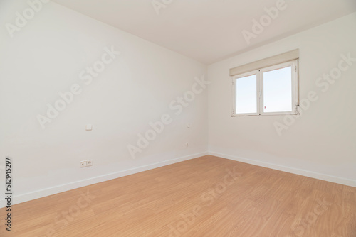 Empty room with light oak flooring, white carpentry on the baseboards and aluminum window with views