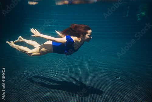 Young woman swimming underwater in the swimming pool