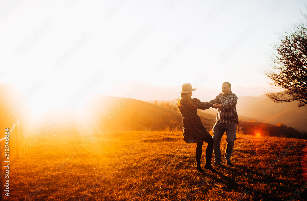 Happy couple circling holding hands enjoying each other at sunset. Holidays in the mountains.