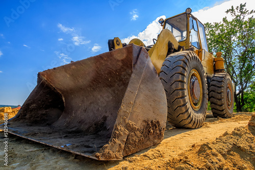 day view of a yellow excavator with a shovel at a construction site