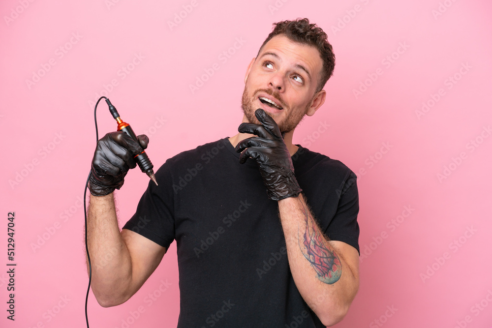 Tattoo artist brazilian man isolated on pink background looking up while smiling Tattoo artist brazilian man isolated on pink background looking up while smiling