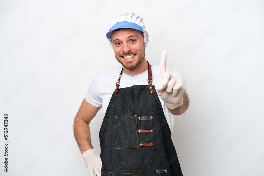Fishmonger man wearing an apron isolated on white background showing and lifting a finger