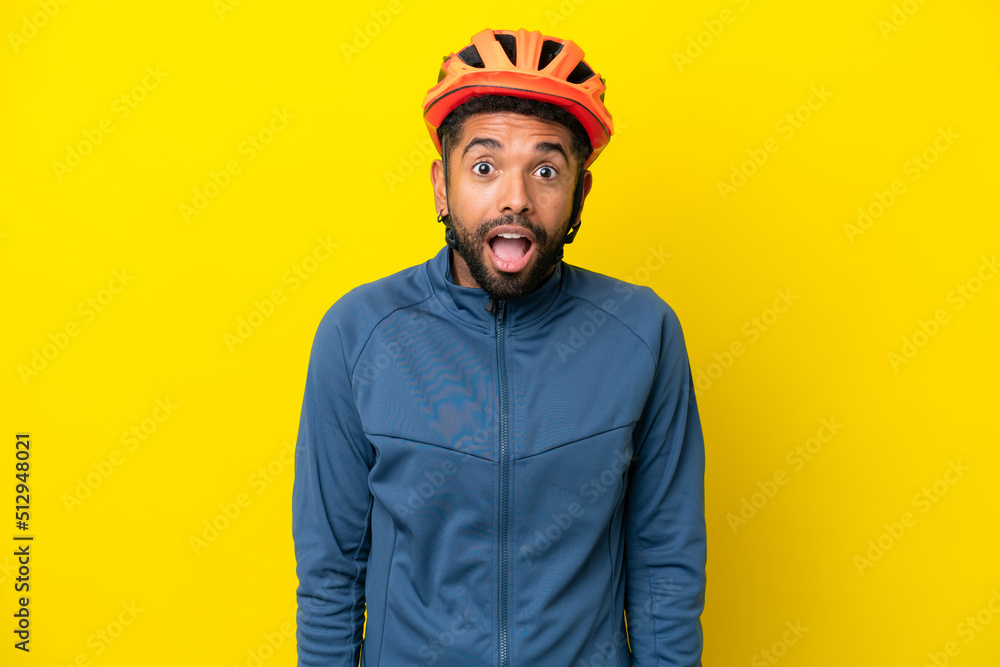 Young cyclist Brazilian man isolated on yellow background with surprise facial expression
