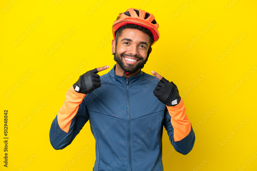 Young cyclist Brazilian man isolated on yellow background giving a thumbs up gesture Young cyclist Brazilian man isolated on yellow background giving a thumbs up gesture