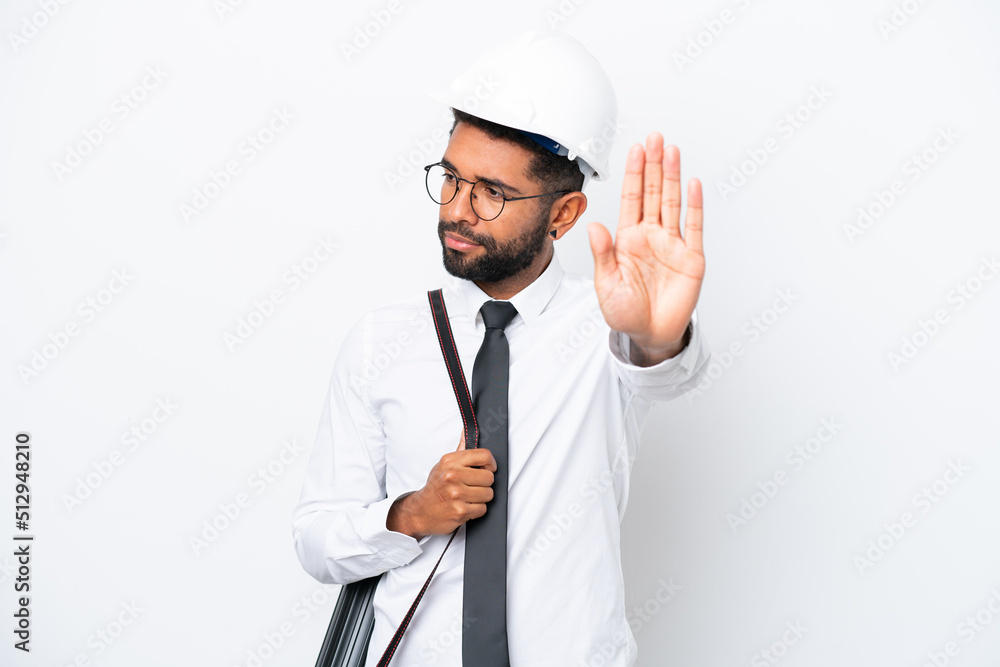Young architect Brazilian man with helmet and holding blueprints isolated on white background making stop gesture and disappointed Young architect Brazilian man with helmet and holding blueprints isolated on white background making stop gesture and disappointed