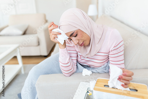 Sick day at home. Young Arabic woman has runny and common cold. Cough. Closeup Of Beautiful Young Woman with hijab Caught Cold Or Flu Illness.