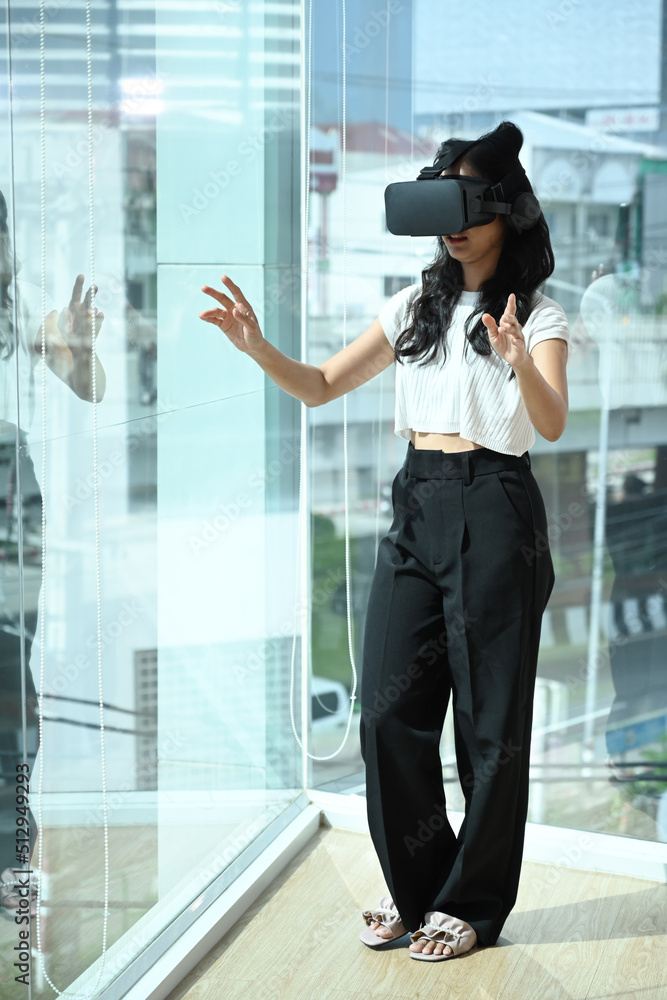 Excited young businesswoman wearing virtual reality headset and interacts with cyberspace. Connection, technology, new generation, progress concept Excited young businesswoman wearing virtual reality headset and interacts with cyberspace. Connection, technology, new generation, progress concept