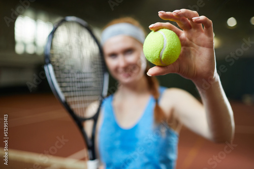Close-up of female player standing on court and showing green tennis ball, focus on ball in hand © Mediaphotos