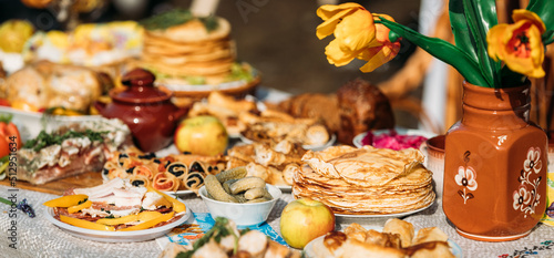 Dishes of the traditional Belarusian cuisine - pancakes, pancakes with caviar, lard, bacon, honey and pickled cucumbers. Attribute of traditional folk celebration of Maslenitsa. Panorama, Panoramic