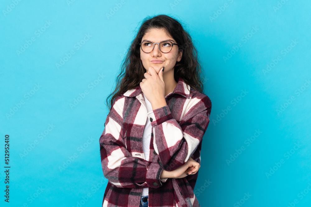 Teenager Russian girl isolated on blue background thinking an idea while looking up Teenager Russian girl isolated on blue background thinking an idea while looking up