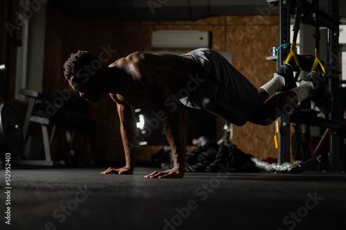 Shirtless afro american man doing exercises with functional loops in the gym.  © Михаил Решетников