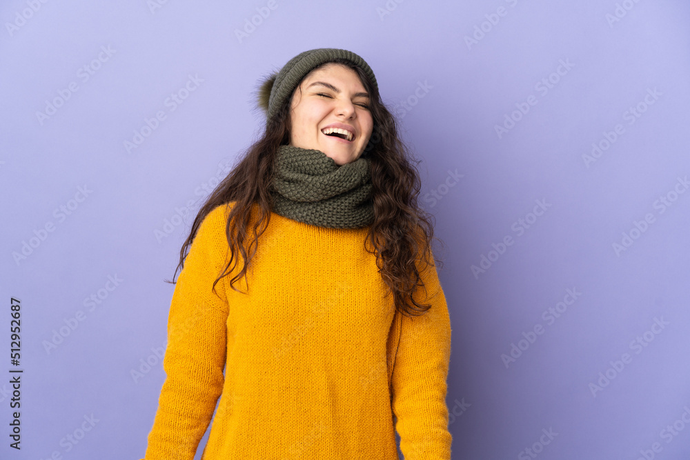 Teenager Russian girl with winter hat isolated on purple background laughing Teenager Russian girl with winter hat isolated on purple background laughing