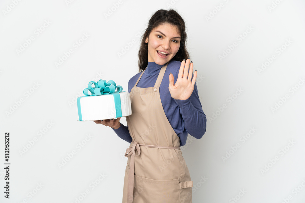 Pastry Russian chef holding a big cake isolated on white background saluting with hand with happy expression Pastry Russian chef holding a big cake isolated on white background saluting with hand with happy expression