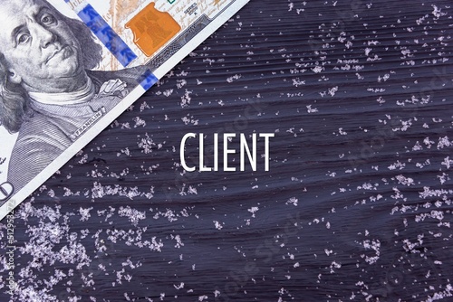 CLIENT - word (text) on a dark wooden background, money, dollars and snow. Business concept (copy space).