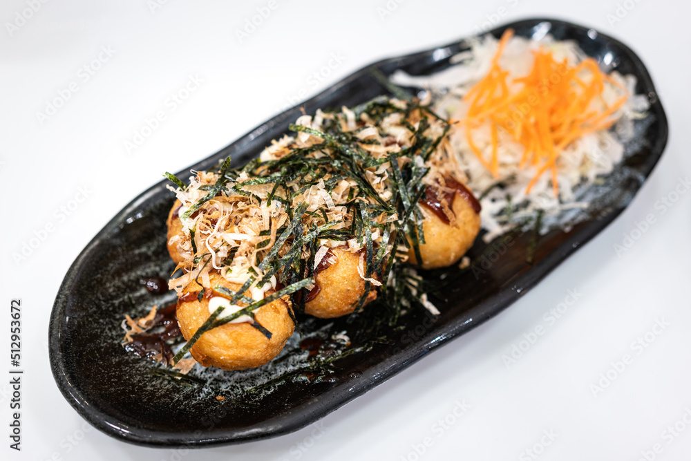 Takoyaki (deep fried squid ball), the most famous japanese snack food, served in black crockery plate. Selective focus at front piece. Takoyaki (deep fried squid ball), the most famous japanese snack food, served in black crockery plate. Selective focus at front piece.
