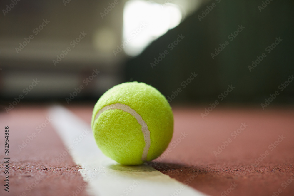 Close-up of green ball lying on white line of tennis court, sport and hobby concept