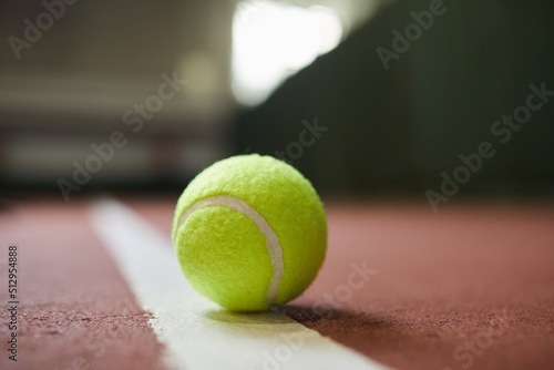 Close-up of green ball lying on white line of tennis court, sport and hobby concept © Mediaphotos
