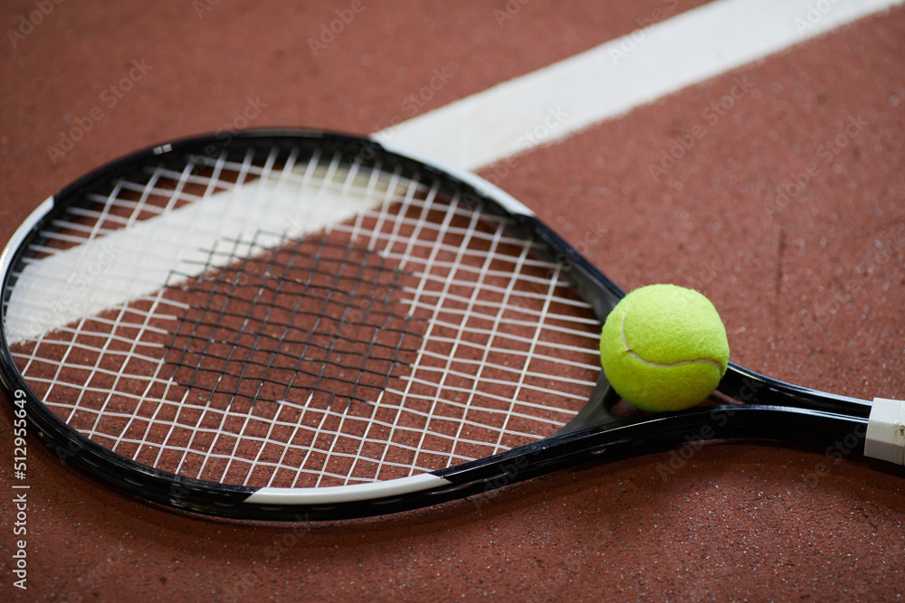 Close-up of tennis sports equipment such as good quality racket and ball lying on floor of court, copy space
