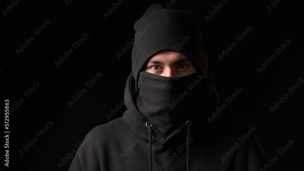 Thief staring at the camera while standing on a dark background. Thief staring at the camera while standing on a dark background.