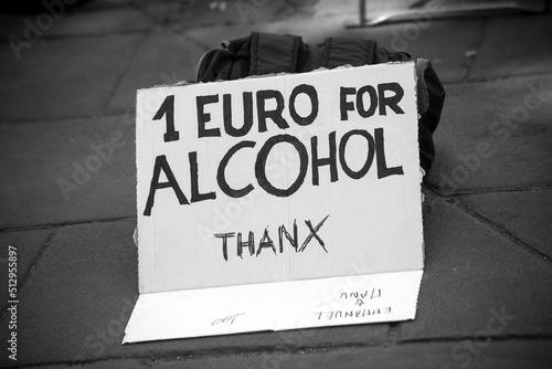 Closeup of homeless man placard with text in english : one euro for alcohol thanks