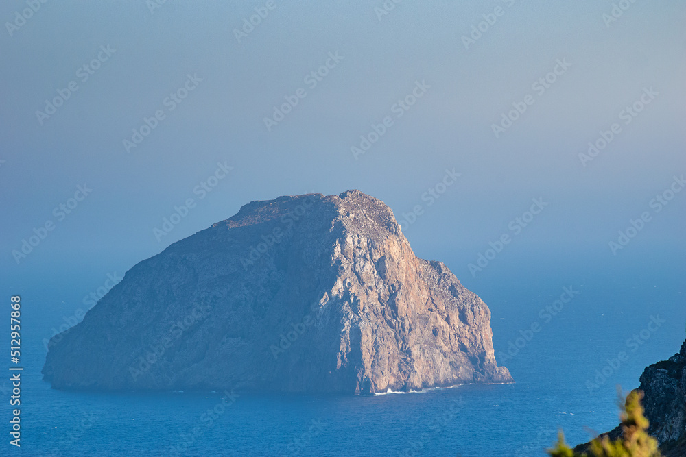 The magical islet of Hytra or else Avgo (Egg) close to Kapsali, Kythera idland. The steep and rocky inhospitable territory is decorated by the yellowish semprevivum, and is also a nesting falcon place
