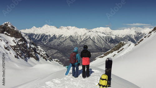 Pair of active man and woman with snowboards at snowy mountains background