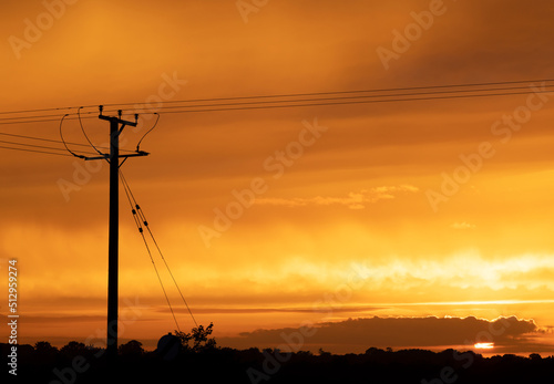 Wooden electricity distribution pole and cables at sunset. UK