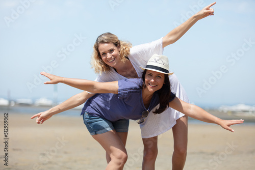 two young female friends walking on the sea shore