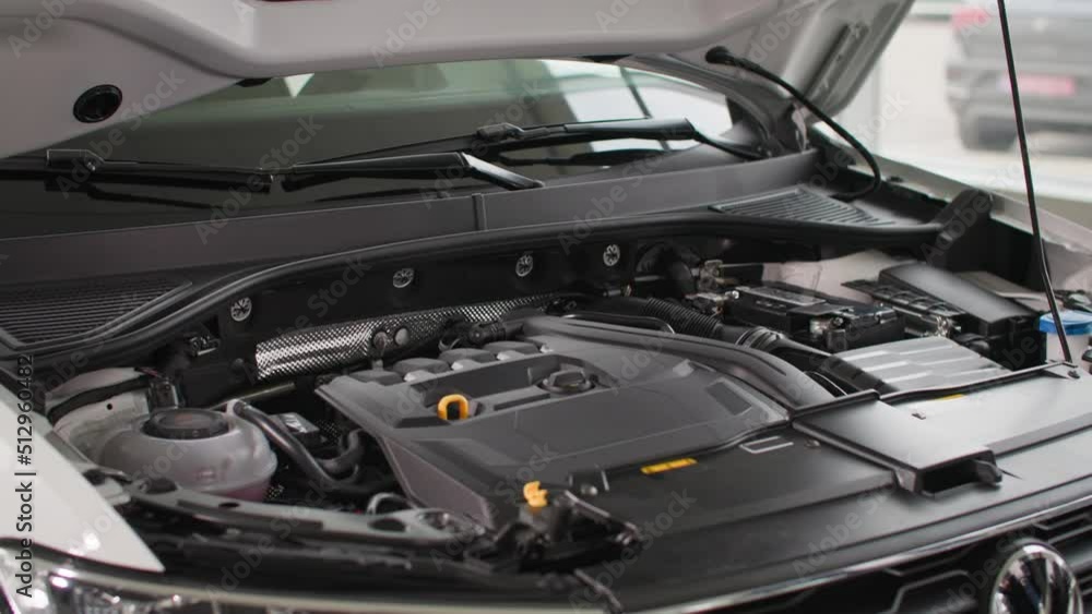 car dealership, exhibition model of a vehicle engine under hood of a new car model in a automobile center, close-up car dealership, exhibition model of a vehicle engine under hood of a new car model in a automobile center, close-up
