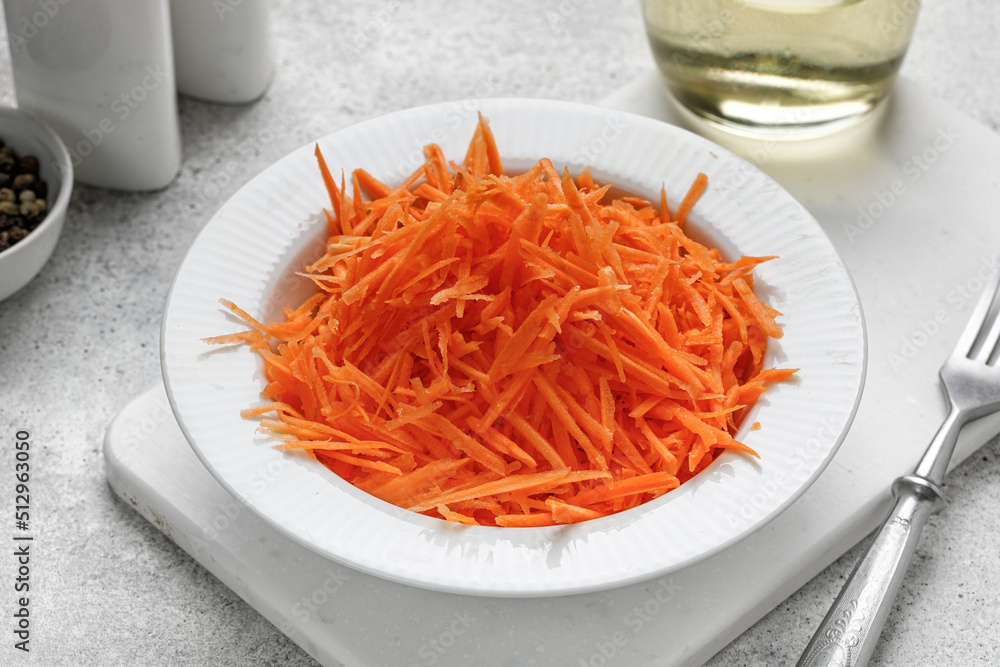 Empty chopped carrot salad in a white bowl. Diet food concept. Detox. Grey background. Empty chopped carrot salad in a white bowl. Diet food concept. Detox. Grey background.
