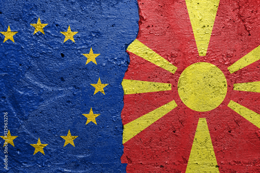 European Union and North Macedonia - Cracked concrete wall painted with a EU flag on the left and a Macedonian flag on the right stock photo
