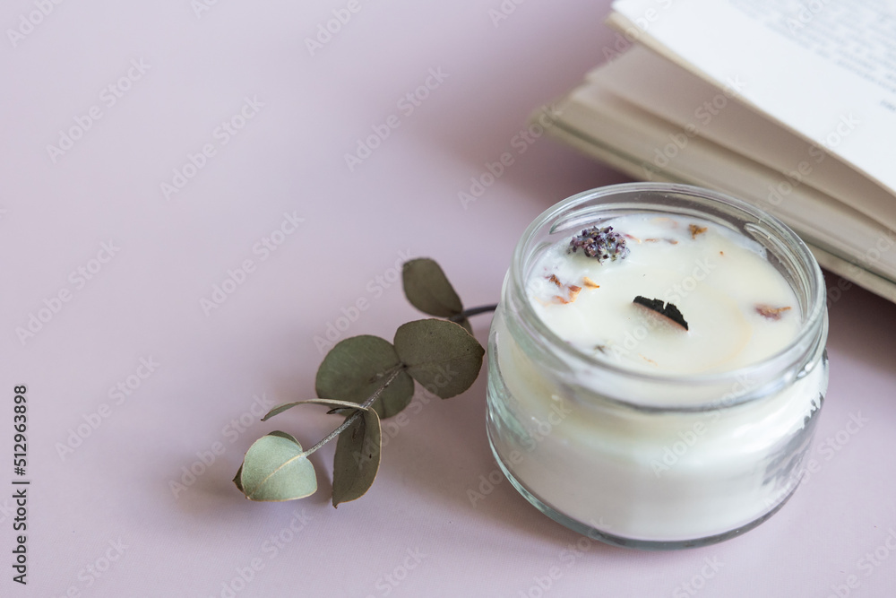 Handmade candle from paraffin and soy wax in glass with wooden wick and dry herbal isolated on pastel pink background. Flat lay, top view, copy space Handmade candle from paraffin and soy wax in glass with wooden wick and dry herbal isolated on pastel pink background. Flat lay, top view, copy space