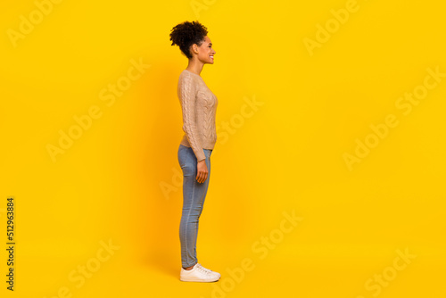 Full length profile photo of young brunette lady look promo wear pullover jeans shoes isolated on yellow background