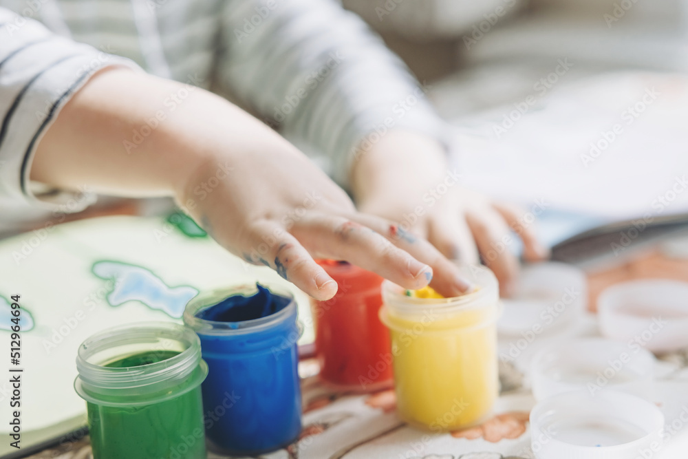 Finger painting. Cute little boy painting with fingers at home. Close-up of child's hand in colorful paints. Early education concept. Sensory play. Development of fine motor skills. Finger painting. Cute little boy painting with fingers at home. Close-up of child's hand in colorful paints. Early education concept. Sensory play. Development of fine motor skills.